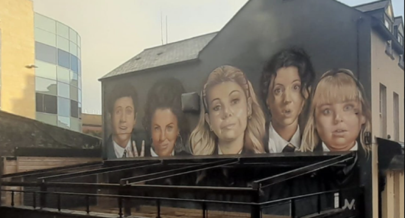 Scaití! Bíonn Doire ag plé le ‘both caith tobac glorified’ ag clúdach go páirteach múrmhaisiú Derry Girls