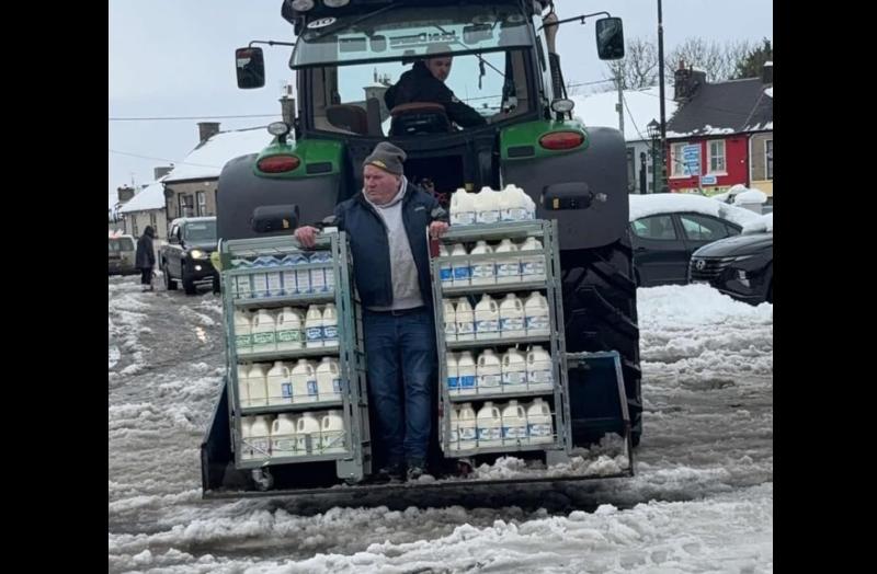 Seachadadh speisialta don siopa i mbaile faoi shneachta agus bainne ag teacht ar chúl an tarracóra